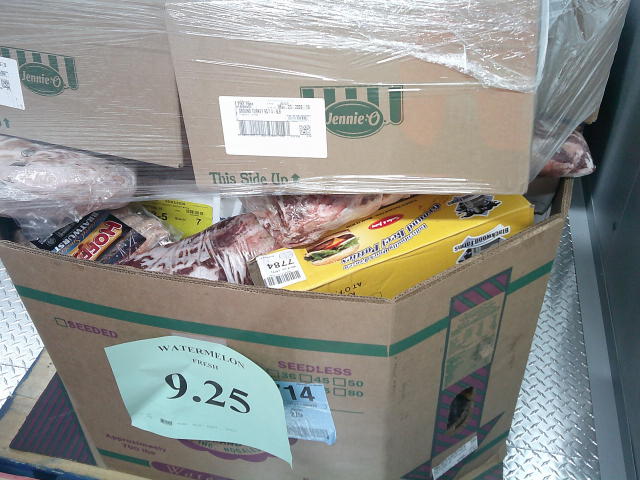 Various meats filled cardboard container with cardboard boxes wrapped in plastic on top.